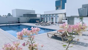 A rooftop pool area with a clear blue pool, lounge chairs, and potted plants. - BW Suites & Spa (Manama)