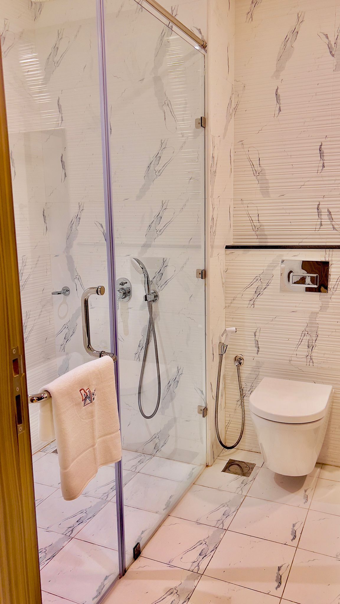 A bathroom with a glass-enclosed shower, a toilet, and a towel rack.