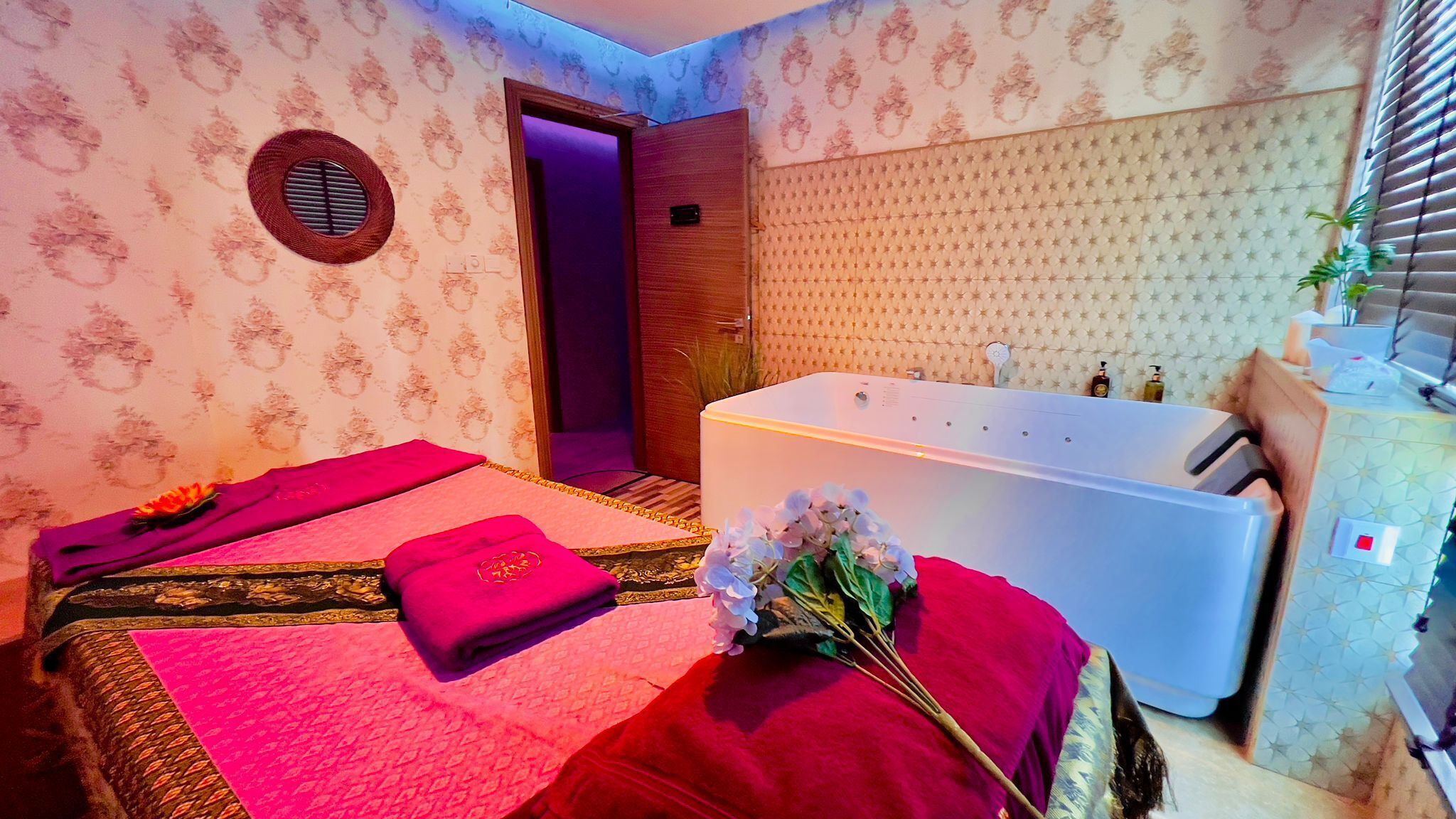 A room with a bed, a massage table, a bathtub, and a small window.