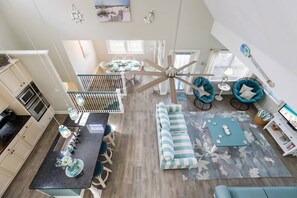 Una cocina moderna con comedor, ventilador de techo y sala de estar con sofá y sillones.