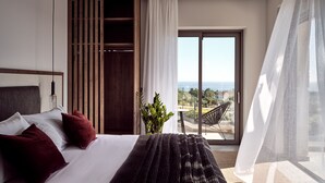 Quarto moderno com uma cama grande, guarda-roupa de madeira e porta de vidro deslizante para uma varanda com vista para o mar.
