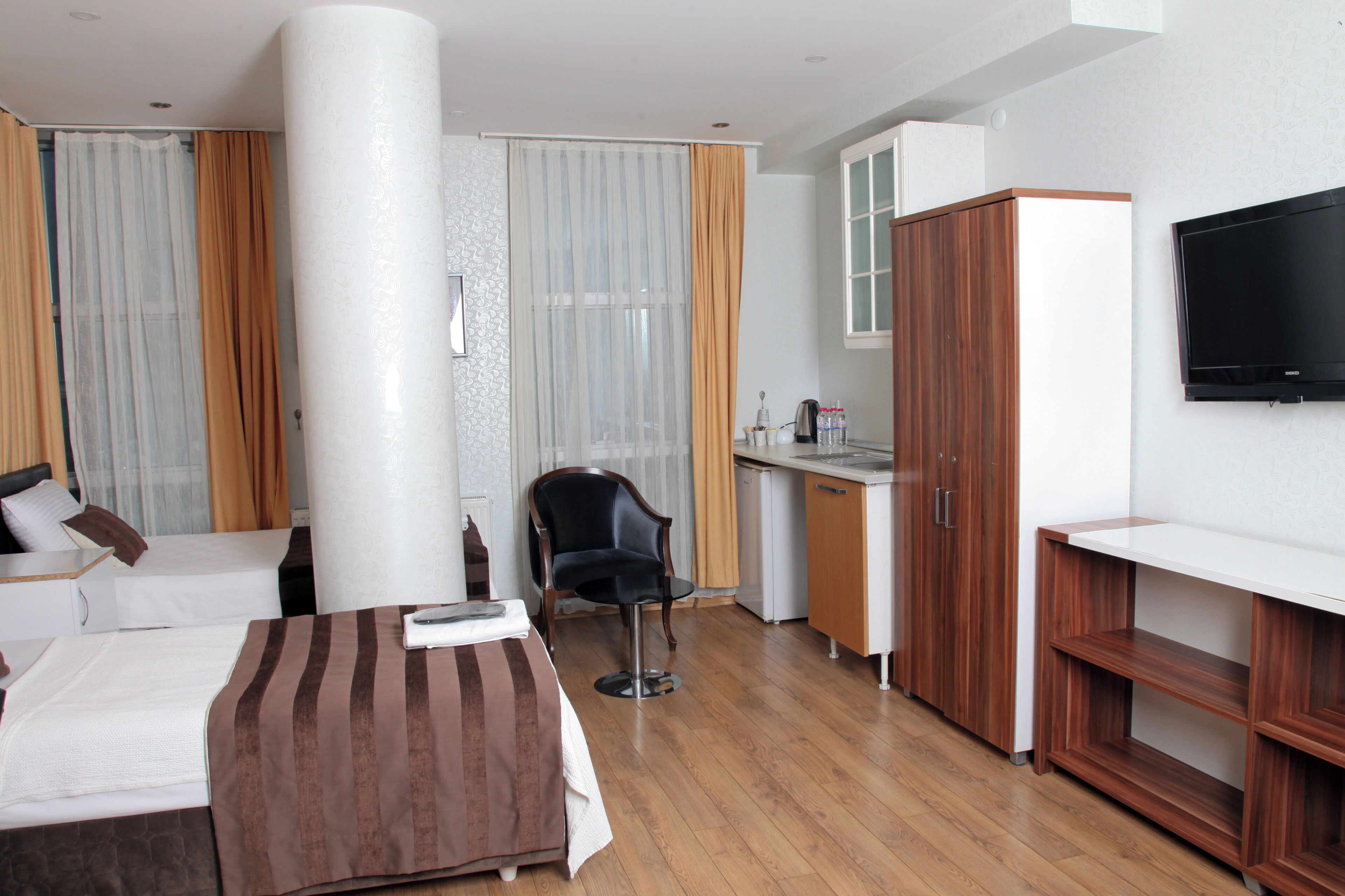 A hotel room with a bed, a desk, a chair, a television, and a wardrobe.