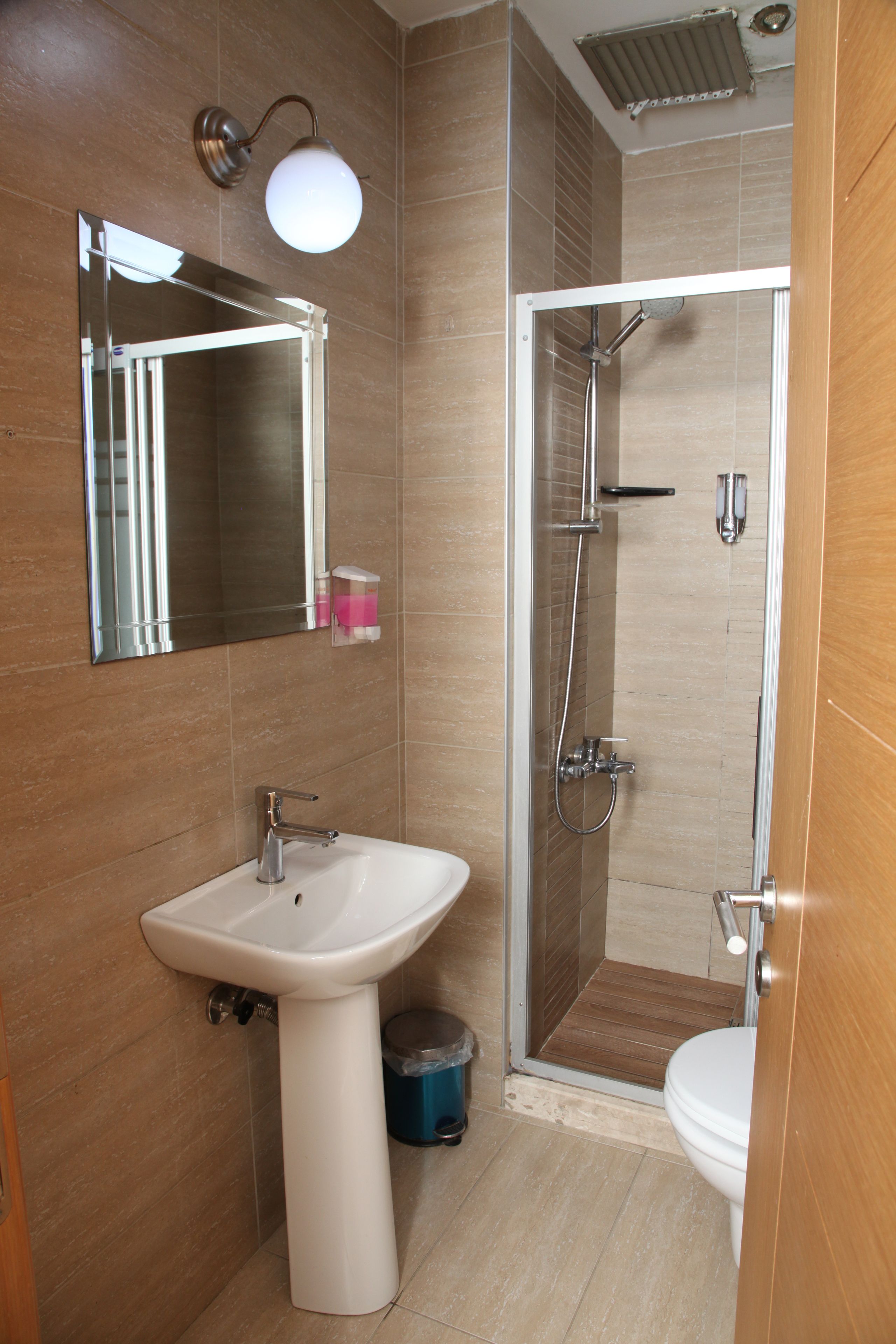 A bathroom with a sink, mirror, shower, and toilet.