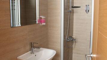 A bathroom with a sink, mirror, shower, and toilet.