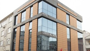 Un hôtel moderne, avec une façade en verre et une enseigne indiquant « Garden Hill Hotel ».