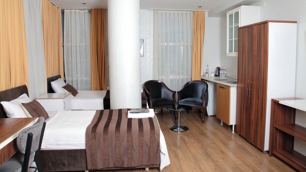 A hotel room with two beds, a desk, a chair, and a wardrobe. - Garden Hill Hotel (Istanbul)
