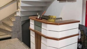 Un comptoir d’accueil avec une pancarte indiquant « RÉCEPTION », un escalier et un meuble placé au-dessus du comptoir.