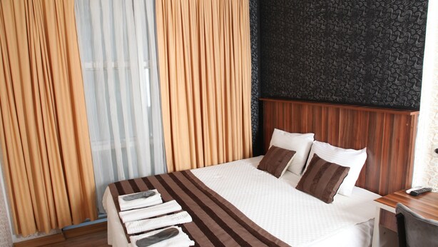 Une chambre d’hôtel équipée d’un lit, d’un bureau, d’une chaise et d’un téléphone.
