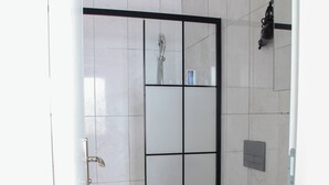 Une salle de bain avec douche, toilettes et lavabo.