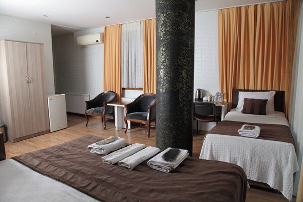 A hotel room with a bed, a desk, a chair, a wardrobe, and a large pillar. - Garden Hill Hotel (Istanbul)