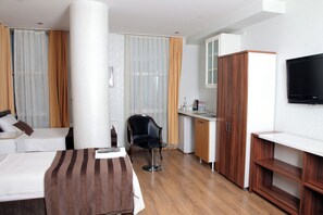 A hotel room with a bed, a desk, a chair, a television, and a wardrobe. - Garden Hill Hotel (Istanbul)
