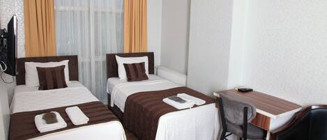 Una habitación de hotel con dos camas individuales, un escritorio pequeño y una silla.