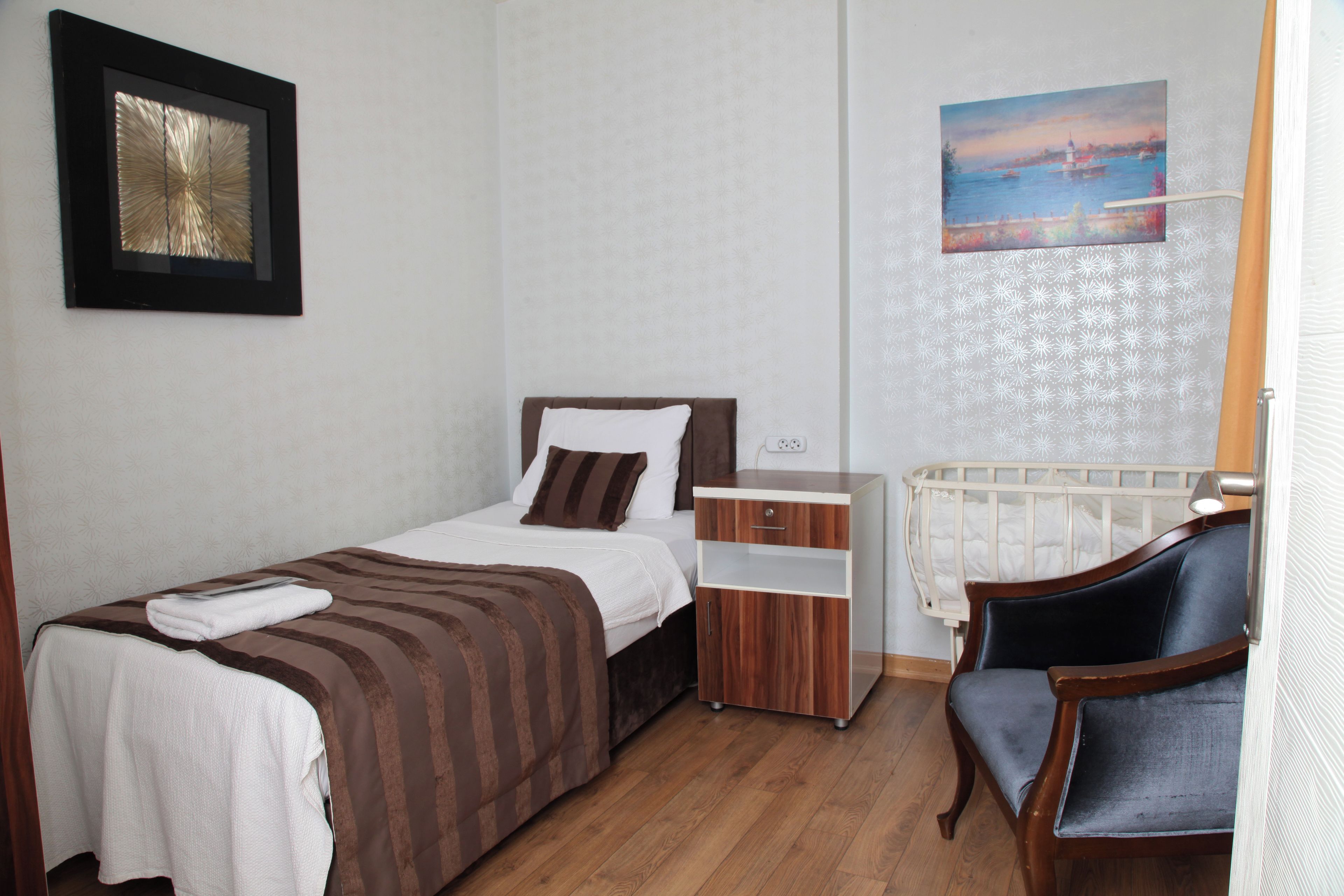 Ein Schlafzimmer mit Bett, Nachttisch, Stuhl und einem Bild an der Wand.