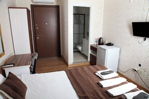 A hotel room with a bed, a desk, a wardrobe, a bathroom, and a TV mounted on the wall. - Garden Hill Hotel (Istanbul)