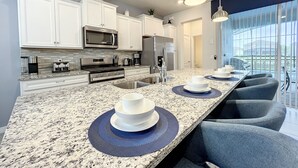 A modern kitchen with white cabinets, stainless steel appliances, and a granite countertop. - 5⭐ Solterra Villa with Lake View • 20 Minutes to Disney (Davenport)