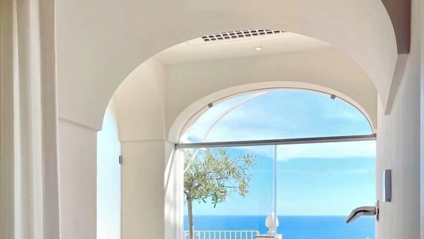 Un'area benessere con vasca idromassaggio, una bottiglia di champagne e un bicchiere su un balcone con vista sul mare.