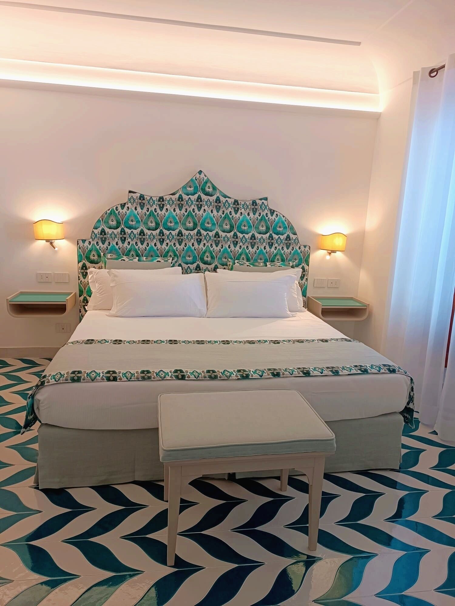 A neatly arranged hotel room with a bed, bedside tables, and a small table.