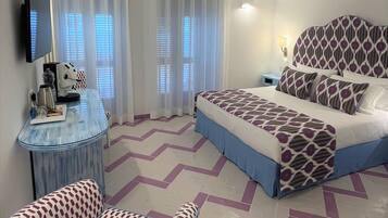 A bedroom with a bed, a desk, a chair, and a TV.