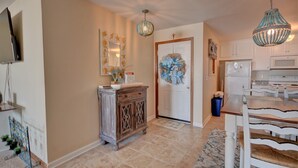 A modern kitchen with white cabinets, a dining table with white chairs, and a chandelier. - Experience oceanfront living at Shipwatch Villas 1209 in North Topsail Beach! (North Topsail Beach)