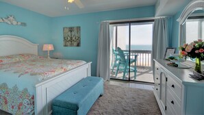 A bedroom with a bed, a bench, a dresser, a desk, and a view of the ocean. - Experience oceanfront living at Shipwatch Villas 1209 in North Topsail Beach! (North Topsail Beach)