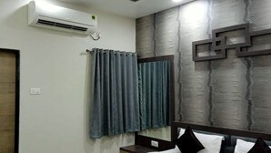 Quarto de hotel com cama, ar condicionado fixado na parede e cortina.