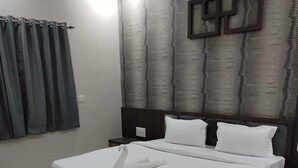 Cama bem arrumada com lençóis brancos e travesseiro decorativo em formato de cisne, parede estampada e tapete geométrico.