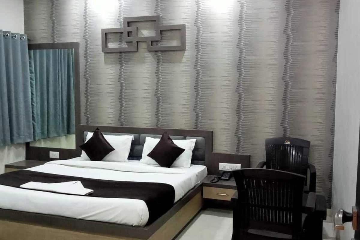 A modern hotel room with a large bed, a desk, a chair, and a wall-mounted TV.