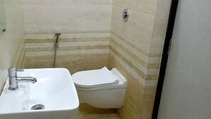 Casa de banho pequena com lavatório, sanita e chuveiro, tudo em branco.