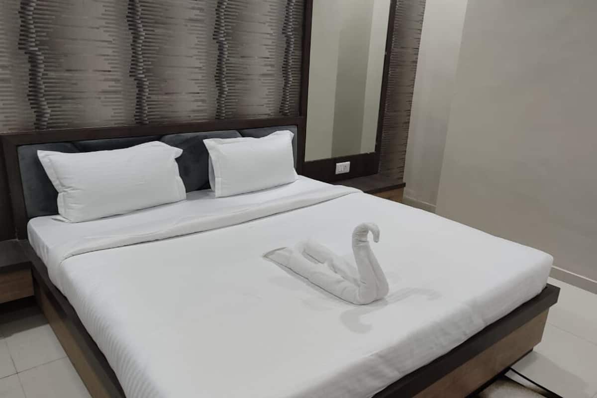 A neatly made bed with white linens and a swan-shaped pillow.