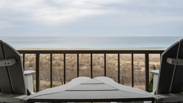 A deck with two chairs facing a beach view. - Great Oceanfront 1 Bedroom in Desirable North Ocean City (Ocean City)