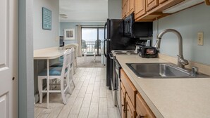 A kitchen with wooden cabinets, a black microwave, and a stainless steel sink. - Great Oceanfront 1 Bedroom in Desirable North Ocean City (Ocean City)