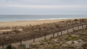 A beach with a wooden fence and a sign indicating closure. - Great Oceanfront 1 Bedroom in Desirable North Ocean City (Ocean City)
