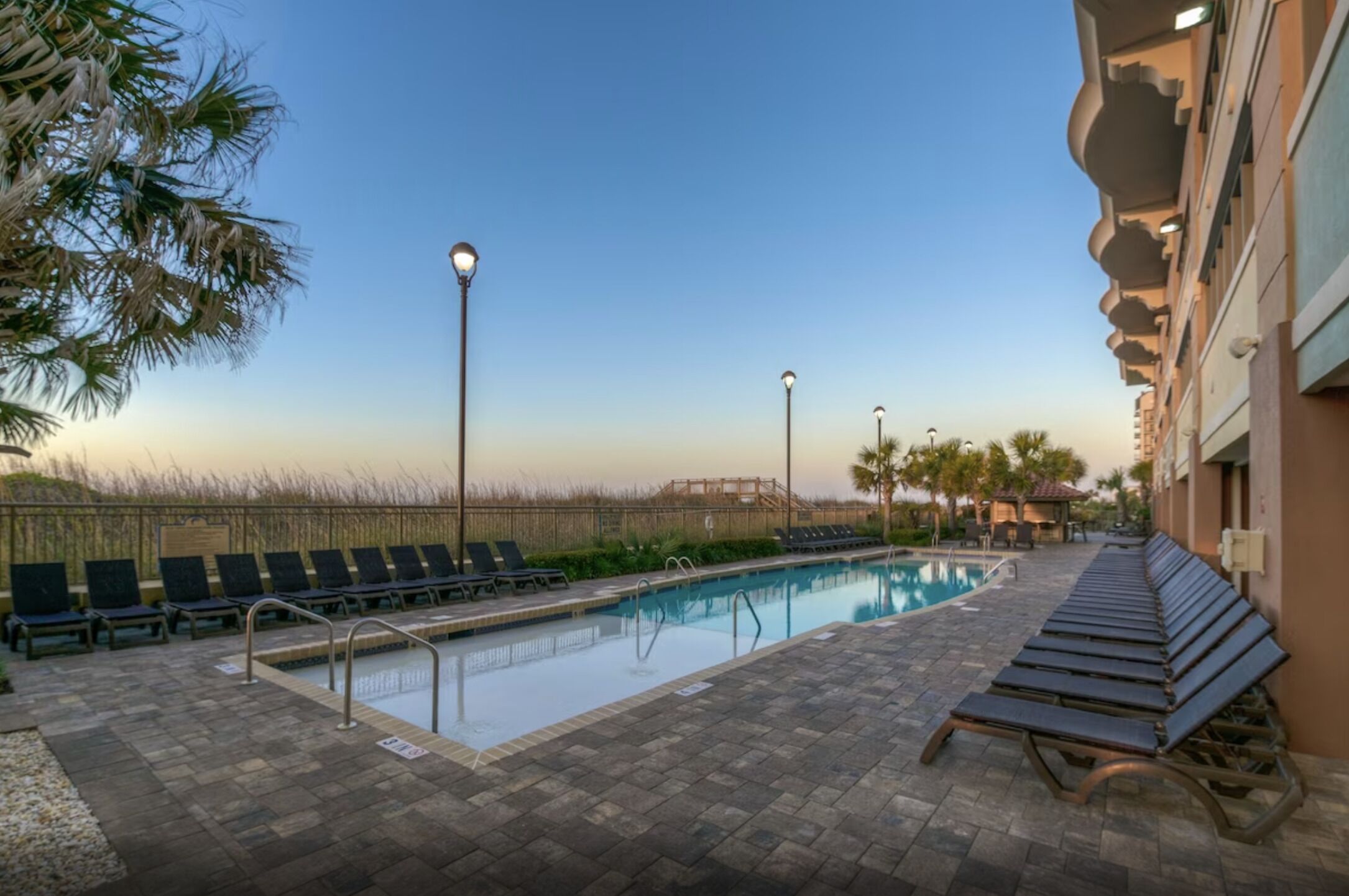 A swimming pool area with lounge chairs and a wooden deck.