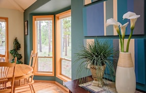 A dining area with a wooden table and chairs, a potted plant, and a vase with flowers. - 27 Cypress Lane-Sunriver, Oregon: Hot Tub, BBQ, WiFi, SHARC Aquatics, Tubing Hill, Mt. Bachelor, Golf, Deschutes River, Tennis, Bike Paths (Sunriver)