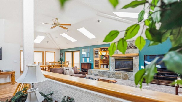 Un salon spacieux avec un haut plafond, une cheminée, un coin repas et un téléviseur.