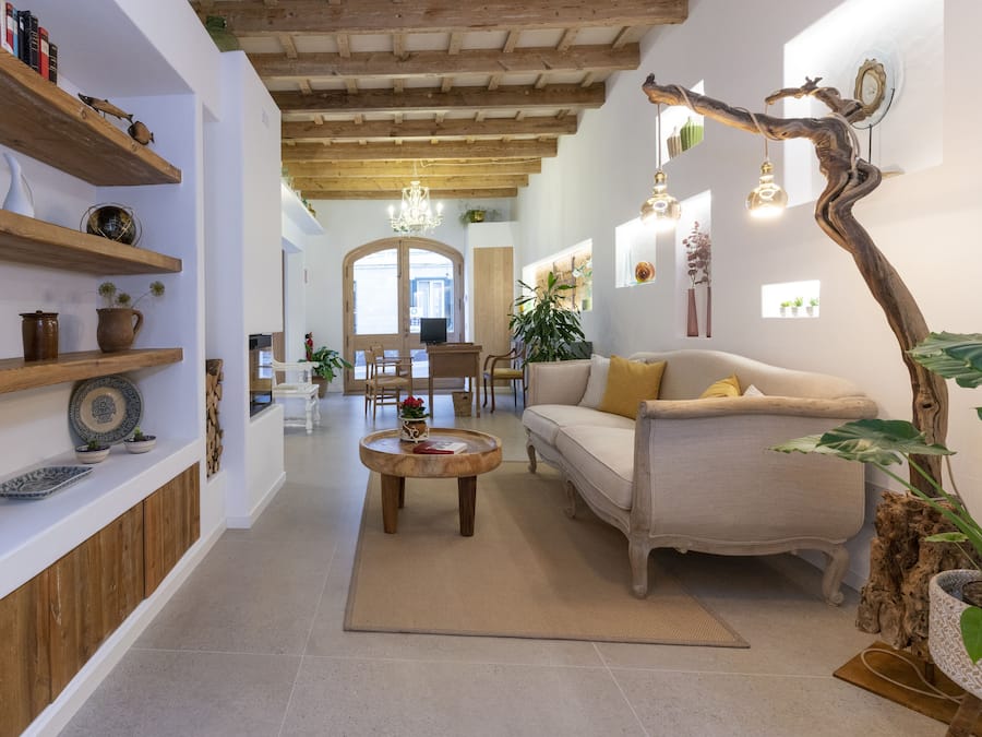 Una sala de estar acogedora con sofá, una mesa de centro y estanterías de madera con adornos.