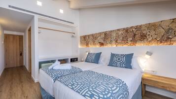 A modern hotel room with a large bed, a stone accent wall, and a wooden floor.