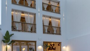 Un edificio moderno con piscina, zona de estar al aire libre y ventanas amplias con cortinas.