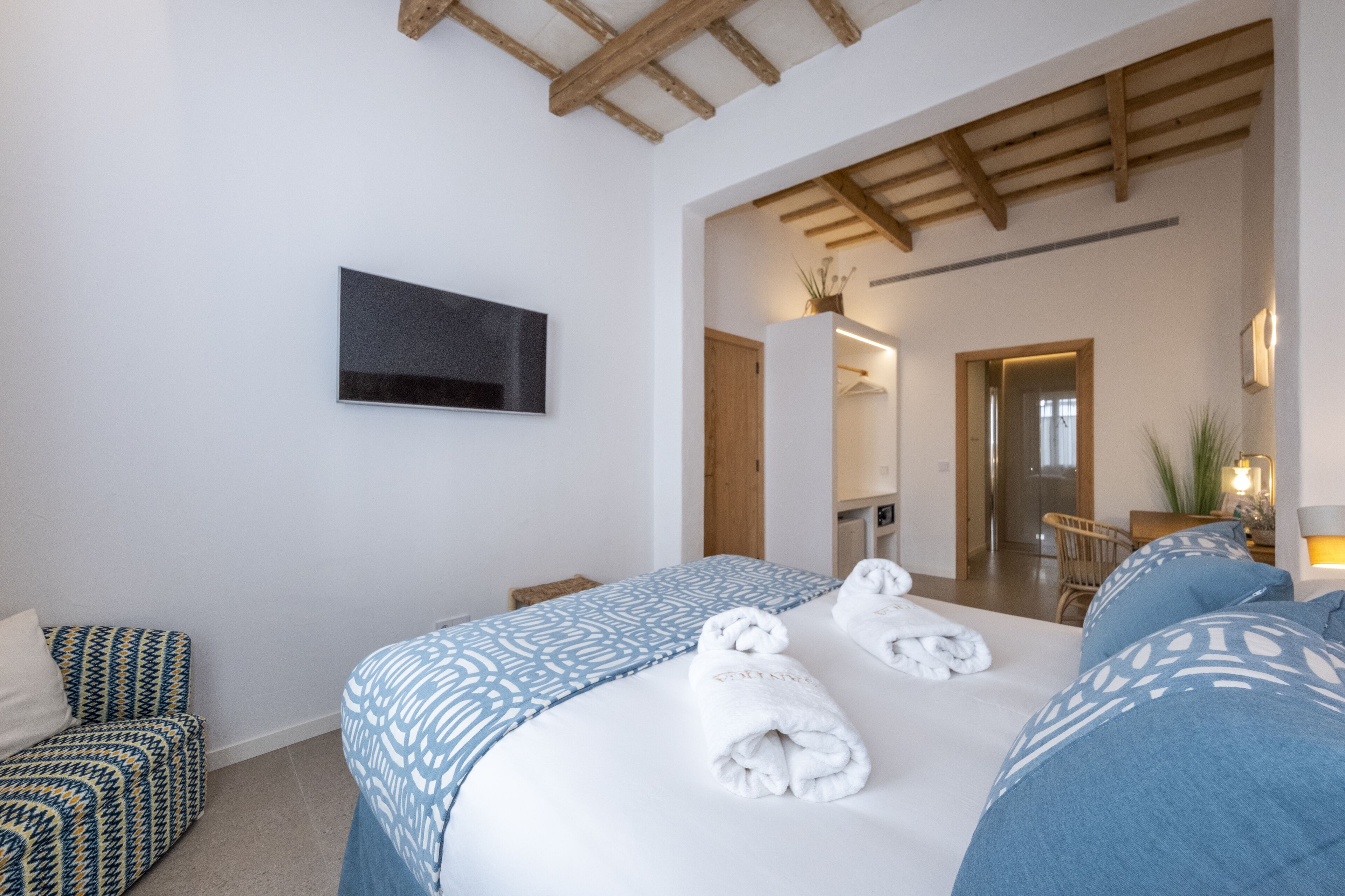 Una habitació d'hotel amb un llit gran, un televisor fixat a la paret i un sostre de fusta.