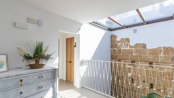 Une pièce avec une commode blanche, une plante en pot, une porte en bois et un mur en briques.