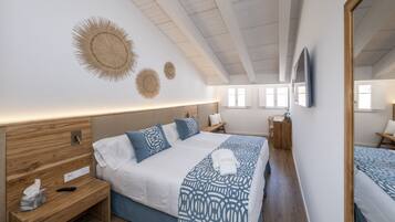 A modern hotel room with a large bed, bedside tables, a mirror, and a ceiling with wooden beams.