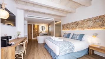Un dormitorio moderno con una cama grande, un escritorio de madera, un espejo redondo y una pared de acento de piedra.