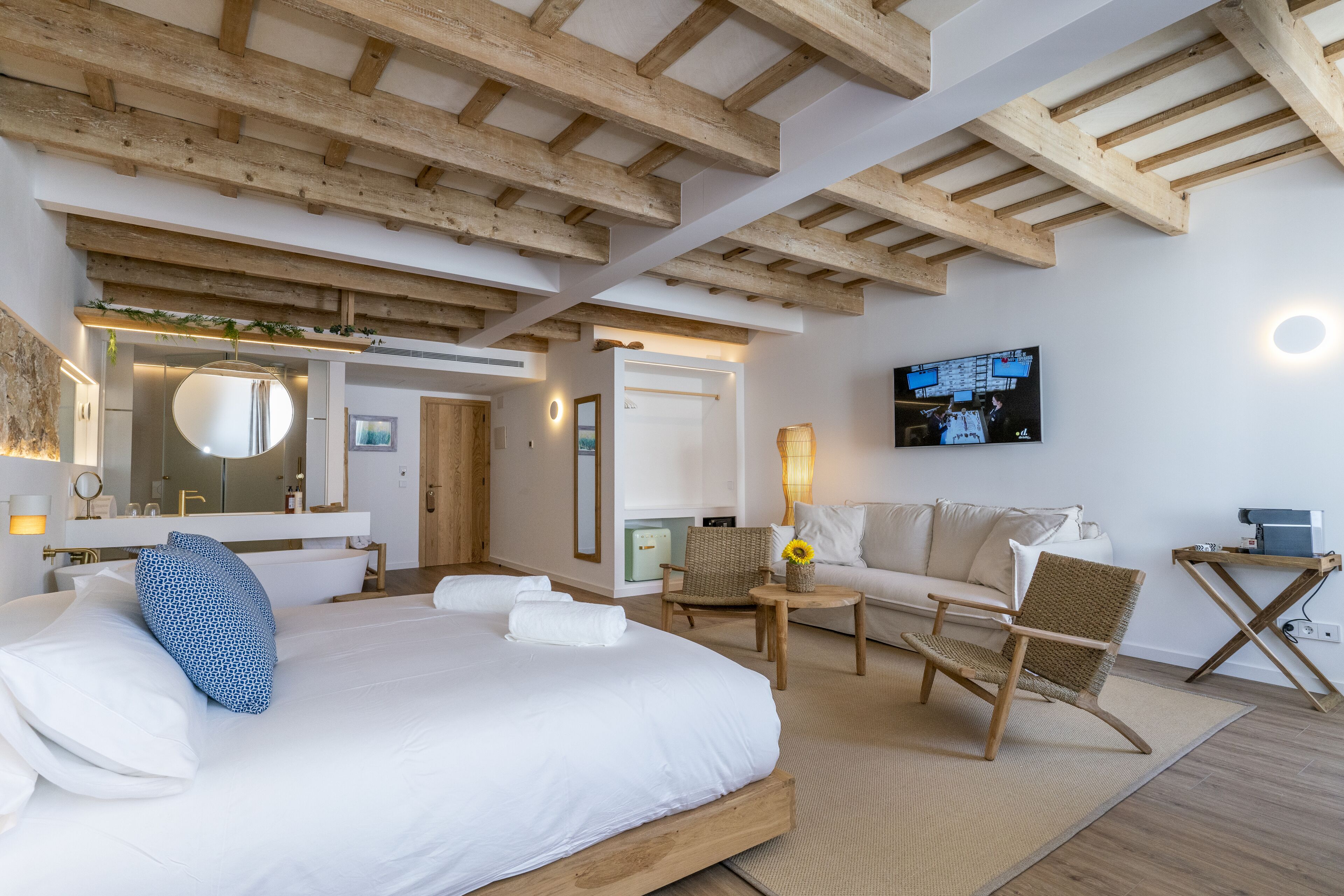 Una habitación de hotel moderna con una cama grande, un sofá, una silla y un televisor.