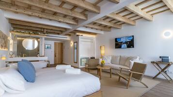 Una habitación de hotel moderna con una cama grande, un sofá, una silla y un televisor.