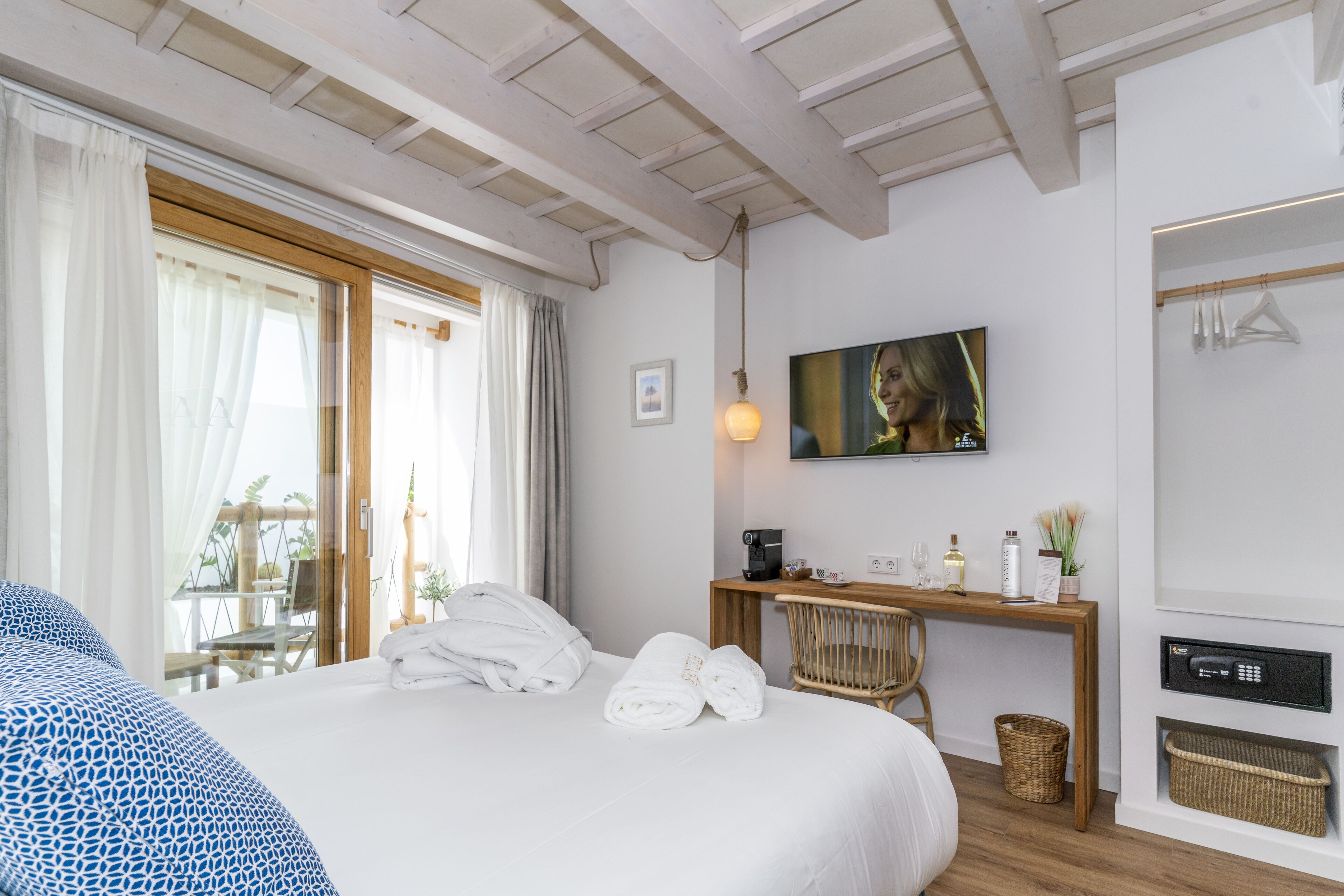 A hotel room with a bed, a desk with a coffee machine, a TV, and a wardrobe.