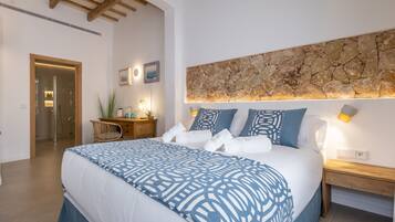 A modern bedroom with a large bed, a stone accent wall, and a wooden ceiling.