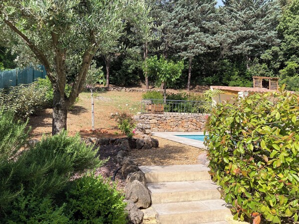 A garden with a stone wall, a small pool, and a wooden deck. - Provençal Villa (Le Thoronet)