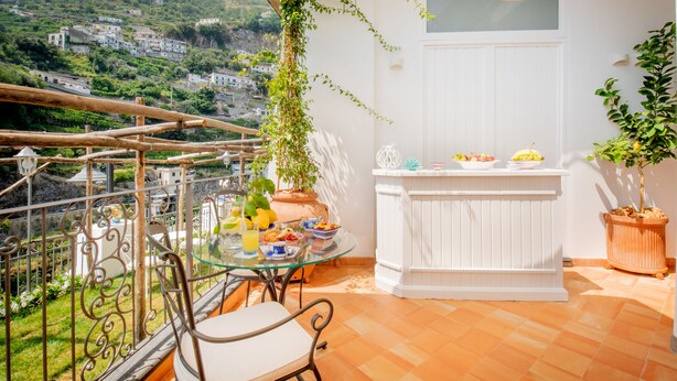 Un balcon avec une table en verre, des chaises et un pot de fleurs.