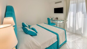 Une chambre d’hôtel avec un lit, un bureau, une chaise, une télévision et une fenêtre avec des rideaux.