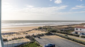 Uitzicht op de kust met een strand, een parkeerplaats en een gebouw met een rood dak.